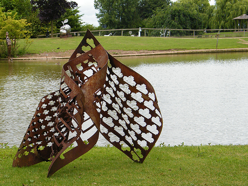 Metal sculpture title Trinity viewed by lake